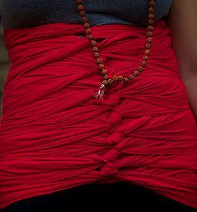 red malaysian abdominal binder wrapper on person wearing mala necklace.  north jersey tummy firming wrap.  nj corset wrap.  postpartum corset to help diastasis recti