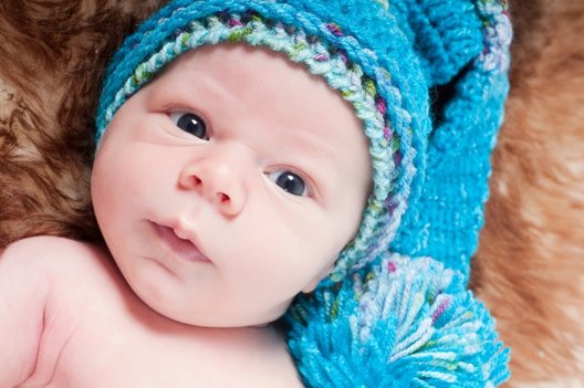 adorable newborn wearing pom pom hat looking at camera, to help you find the best birth class in north jersey, morristown, mount olive, westfield, nyc